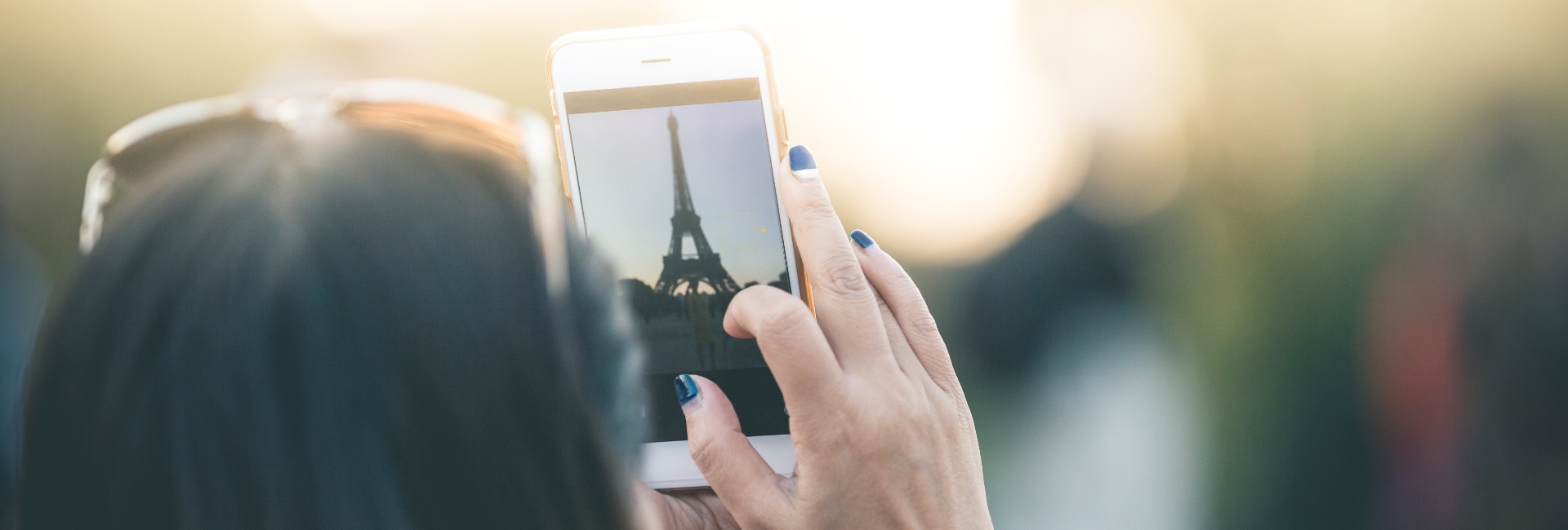 Frau fotografiert Eifelturm mit Smartphone